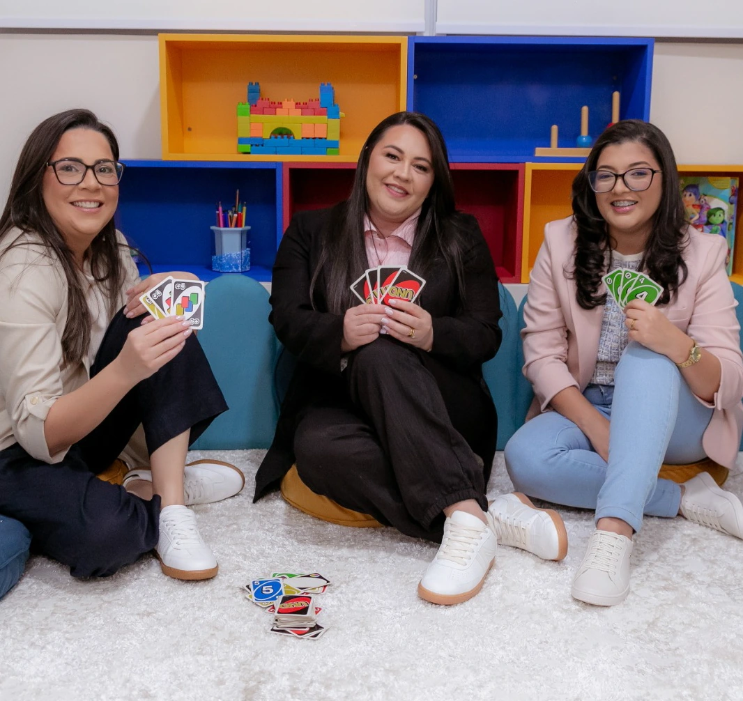 Três profissionais da Psycomind com cartas na sala da clínica